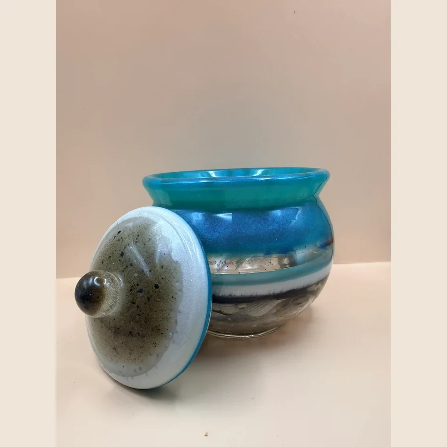 Dit handgemaakte sierpotje met deksel heeft prachtige blauw-, zand- en parelmoertinten die doen denken aan zee, strand en lucht. Door de glanzende afwerking en de zachte kleurverloopjes krijgt het potje een unieke, luxe uitstraling. Het potje is perfect om kleine spulletjes in te bewaren, zoals sieraden, elastiekjes, bedeltjes, paperclips of andere kleine schatten.